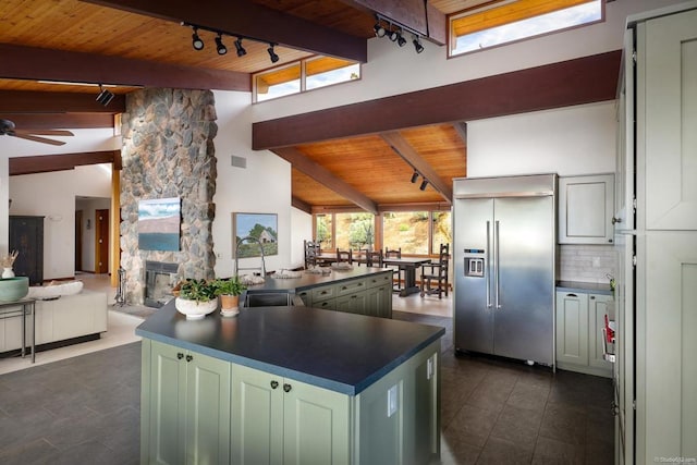 kitchen with open floor plan, dark countertops, built in fridge, and green cabinetry