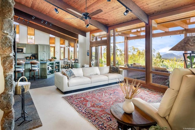 sunroom / solarium with a mountain view, track lighting, wood ceiling, and a ceiling fan