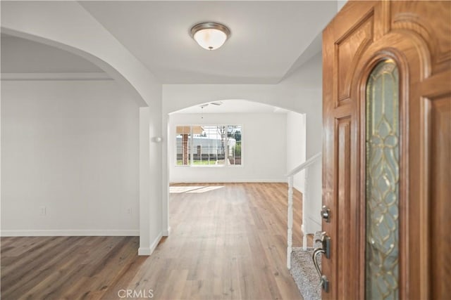 entryway featuring light wood-style flooring, arched walkways, and baseboards