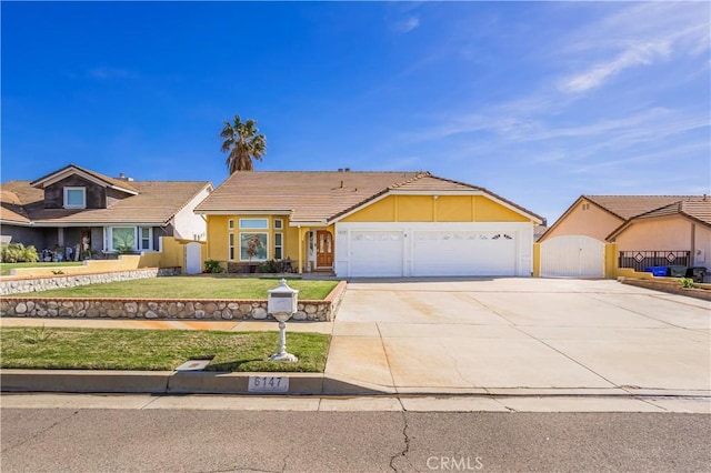 ranch-style home with an attached garage, a tile roof, concrete driveway, stucco siding, and a front lawn