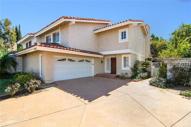 view of front of home featuring stucco siding, a tile roof, concrete driveway, and a garage