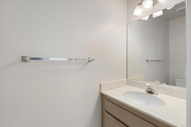 bathroom featuring toilet, visible vents, and vanity