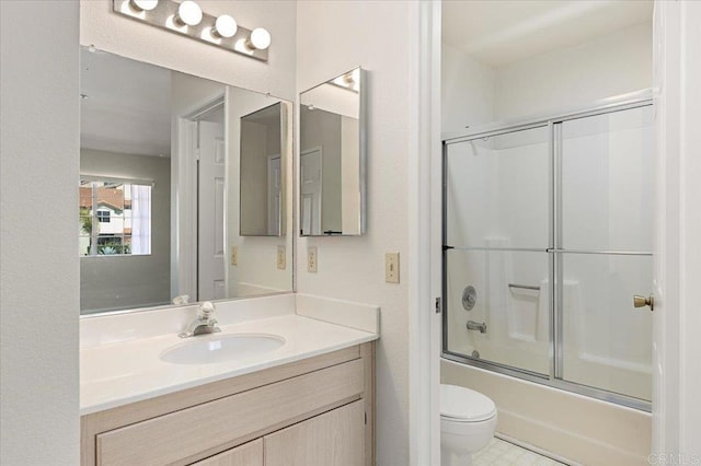 bathroom with vanity, toilet, and bath / shower combo with glass door