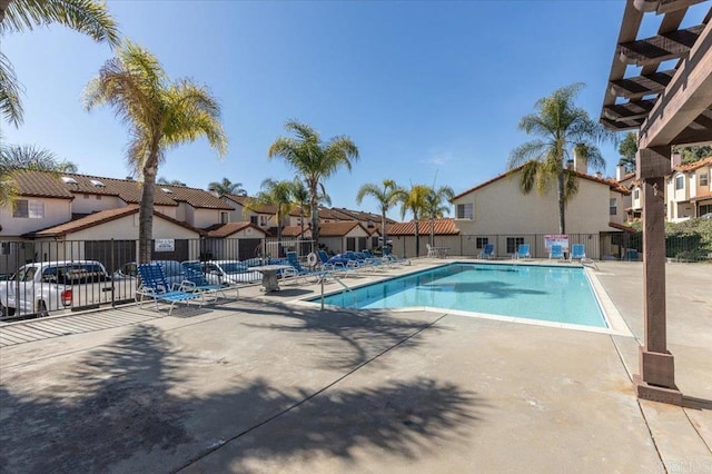 community pool featuring a patio, fence, and a residential view