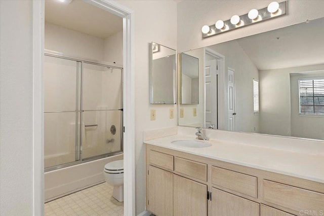 bathroom featuring toilet, vanity, combined bath / shower with glass door, and tile patterned floors