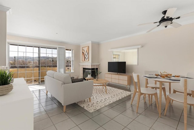 living area featuring light tile patterned floors, ceiling fan, a fireplace, and ornamental molding