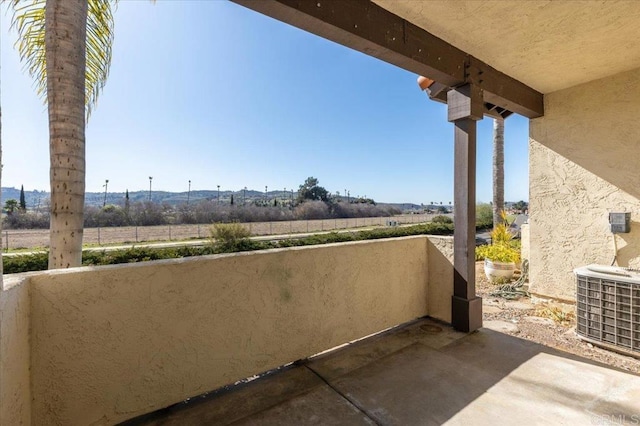 exterior space featuring a rural view, a balcony, and central AC unit