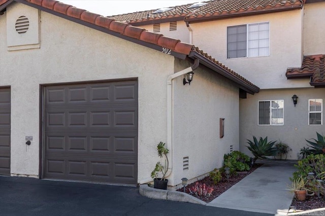 view of home's exterior featuring an attached garage, a tile roof, and stucco siding