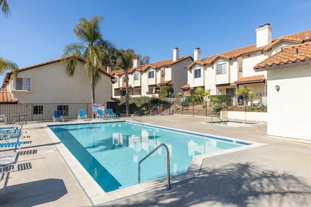 community pool featuring a residential view, fence, and a patio