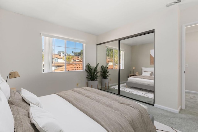 bedroom with a closet, carpet, visible vents, and baseboards