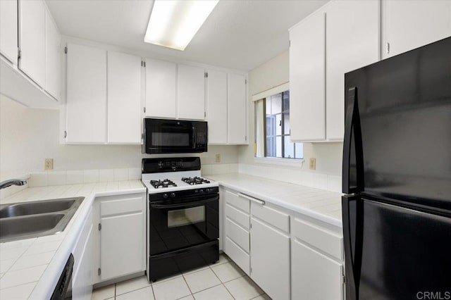 kitchen featuring tile counters, white cabinets, a sink, and black appliances