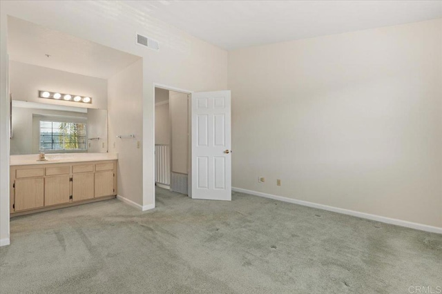 unfurnished bedroom featuring light colored carpet, visible vents, a sink, and baseboards