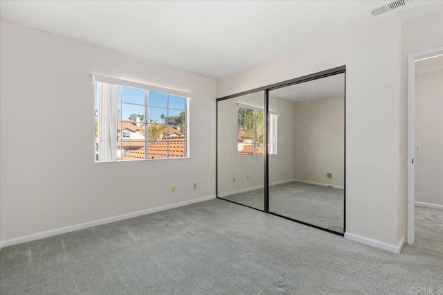 unfurnished bedroom with light carpet, baseboards, visible vents, and a closet