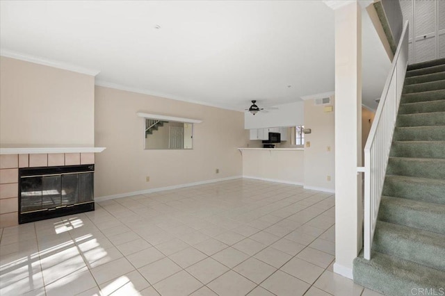 unfurnished living room featuring baseboards, stairway, a tile fireplace, and crown molding