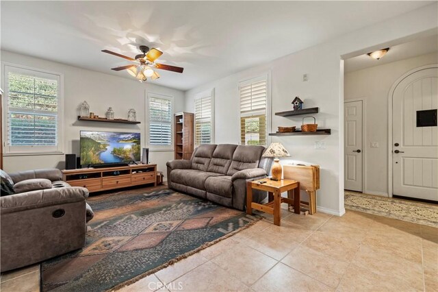 living area featuring ceiling fan, baseboards, and light tile patterned flooring