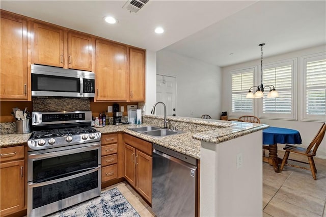 kitchen featuring light tile patterned floors, a peninsula, a sink, appliances with stainless steel finishes, and brown cabinets