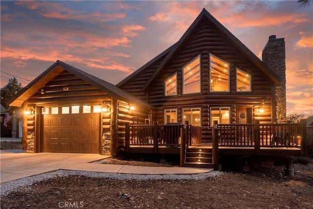 log cabin with a garage, concrete driveway, and a chimney