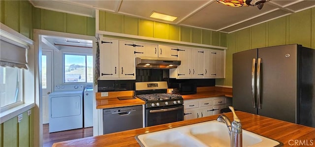 kitchen with butcher block countertops, under cabinet range hood, a sink, separate washer and dryer, and appliances with stainless steel finishes