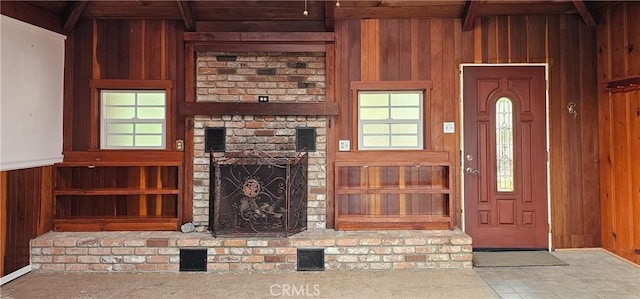 unfurnished living room featuring beamed ceiling, built in shelves, wood walls, and a fireplace