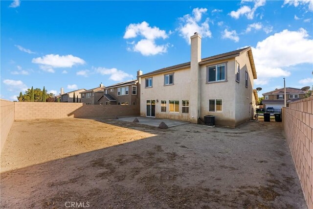 rear view of house featuring a fenced backyard, a residential view, a chimney, cooling unit, and stucco siding