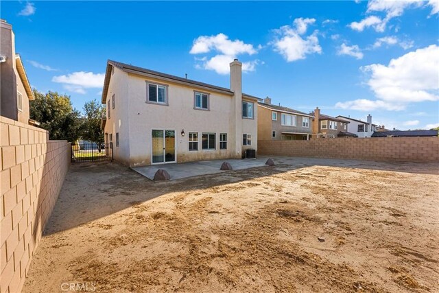 back of property with a fenced backyard, central air condition unit, stucco siding, a chimney, and a patio area