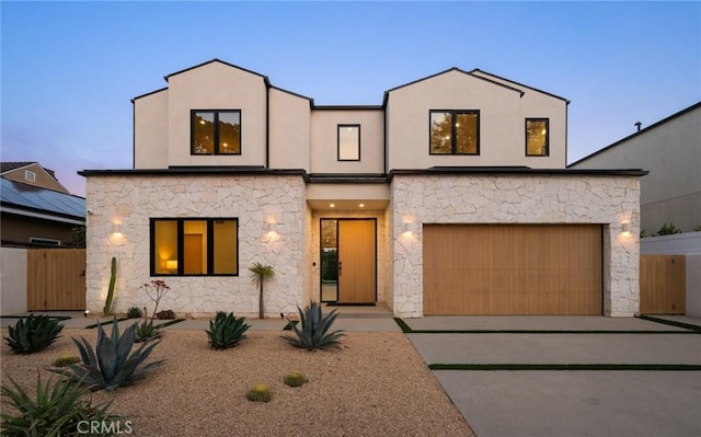 view of front of house with fence, concrete driveway, and stucco siding