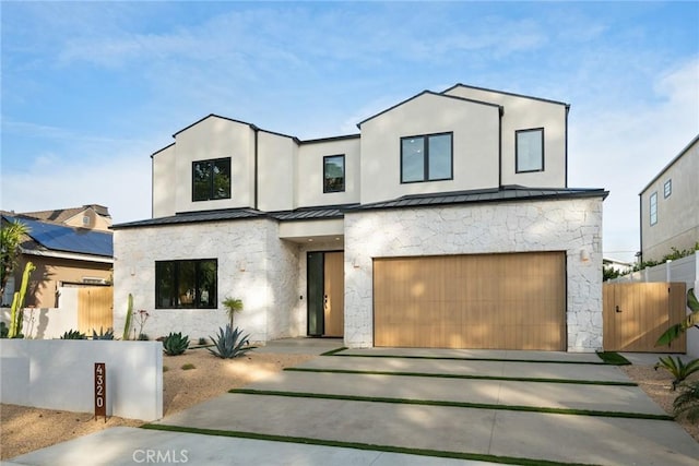 contemporary house with metal roof, an attached garage, fence, concrete driveway, and a standing seam roof