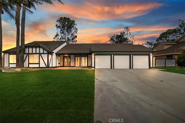 view of front of house with concrete driveway, a lawn, and an attached garage