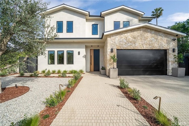 view of front of property featuring a garage, stone siding, decorative driveway, and stucco siding