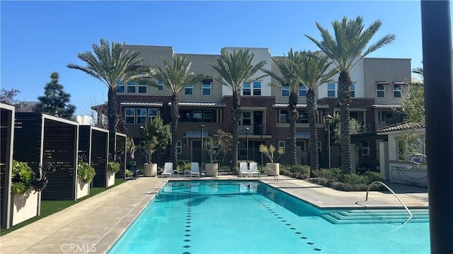 community pool with a patio and fence