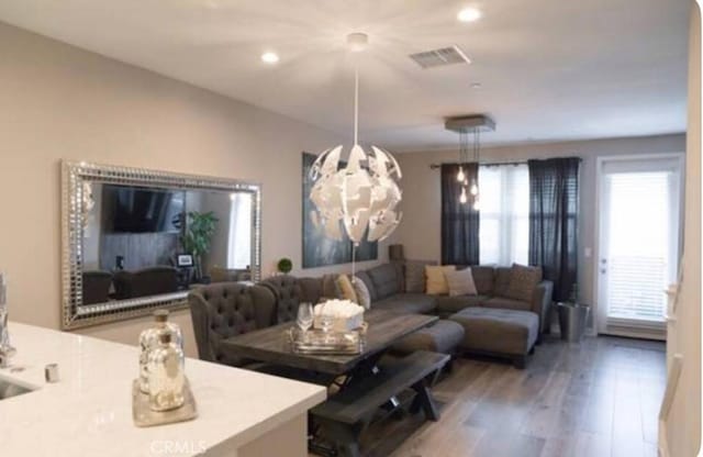 living room featuring a chandelier, wood finished floors, visible vents, and recessed lighting