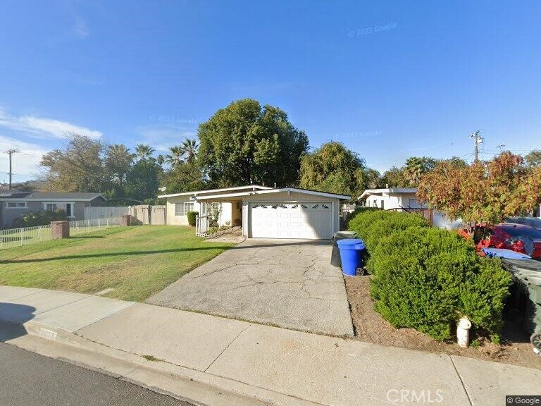 view of front facade featuring a front yard, driveway, an attached garage, and fence