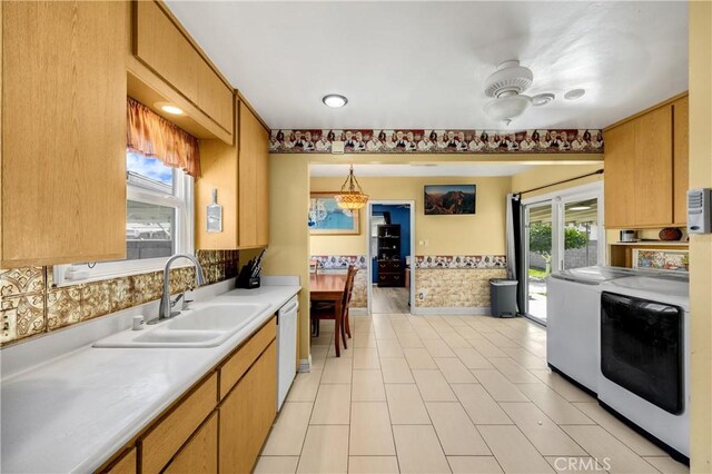 kitchen featuring a wainscoted wall, decorative light fixtures, light countertops, white dishwasher, and separate washer and dryer