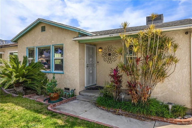 entrance to property featuring a yard and stucco siding