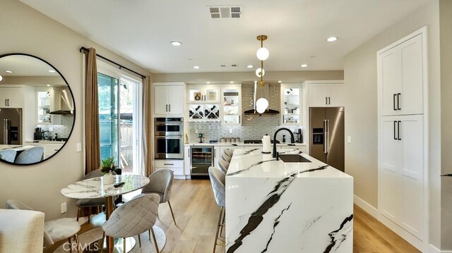 kitchen with white cabinets, glass insert cabinets, light stone counters, stainless steel appliances, and pendant lighting