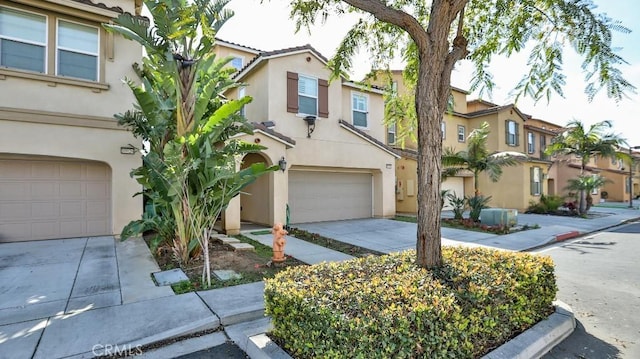 townhome / multi-family property with a garage, a residential view, concrete driveway, and stucco siding