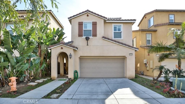 mediterranean / spanish-style house with driveway, a tile roof, a garage, and stucco siding