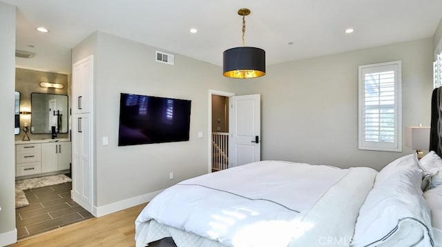 bedroom featuring recessed lighting, visible vents, ensuite bath, wood finished floors, and baseboards