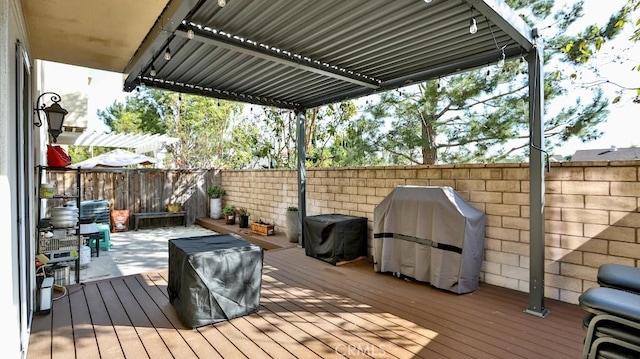 wooden terrace with area for grilling, a fenced backyard, and a pergola