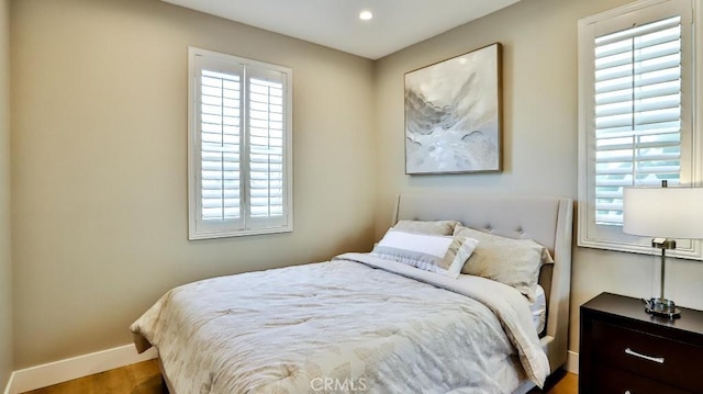 bedroom with baseboards, wood finished floors, and recessed lighting