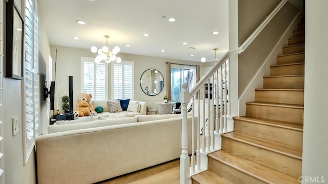 living room with stairs, a notable chandelier, wood finished floors, and recessed lighting