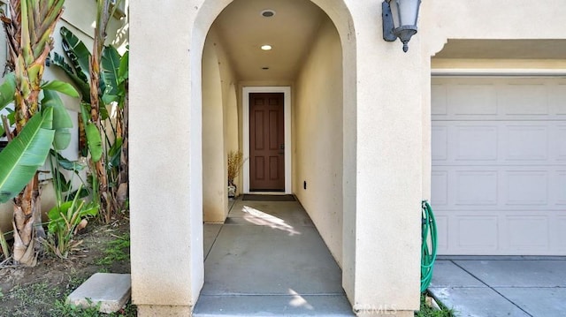 doorway to property featuring a garage and stucco siding