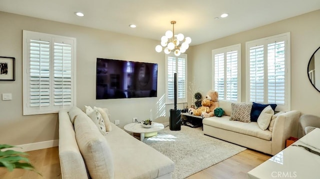 living area featuring a chandelier, light wood finished floors, baseboards, and recessed lighting