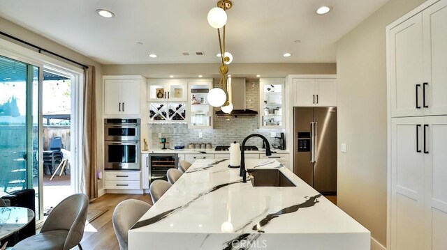 kitchen featuring glass insert cabinets, light stone countertops, appliances with stainless steel finishes, and pendant lighting