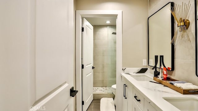 full bath with double vanity, toilet, tile patterned floors, a shower stall, and a sink