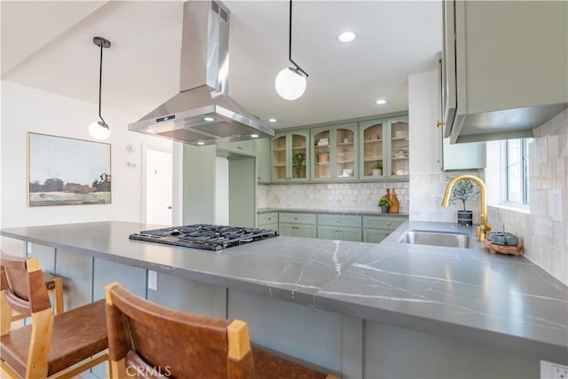 kitchen with hanging light fixtures, a peninsula, glass insert cabinets, and island range hood