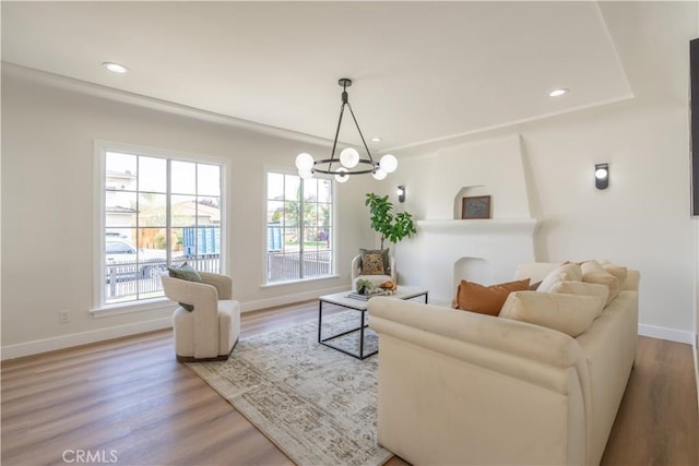 living room with a notable chandelier, baseboards, a wealth of natural light, and wood finished floors