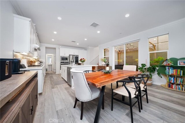 dining space with light wood-type flooring, visible vents, crown molding, and recessed lighting