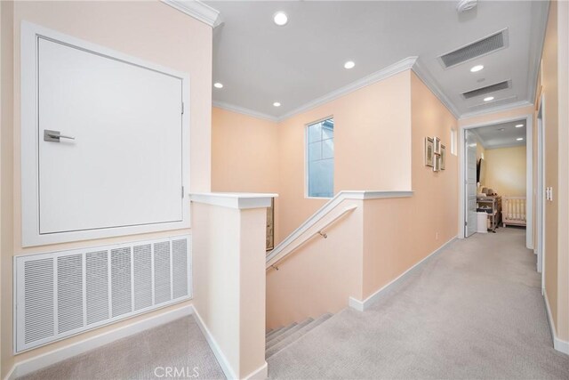 hallway featuring light carpet, visible vents, ornamental molding, and an upstairs landing