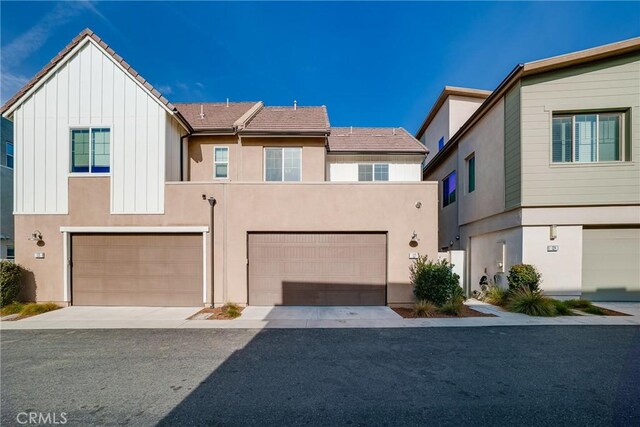 multi unit property featuring driveway, an attached garage, a tile roof, and stucco siding